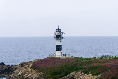 Lighthouse by sea against clear sky