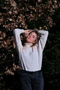 Portrait of young blonde woman standing against plants