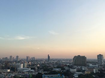 Aerial view of city buildings against sky during sunset