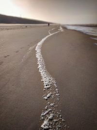 Surface level of sandy beach against sky