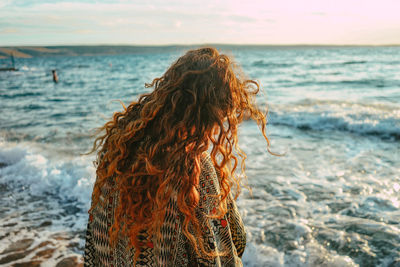 Midsection of woman at beach against sky