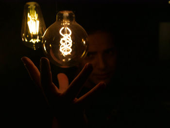 Close-up of man hand under illuminated light bulb