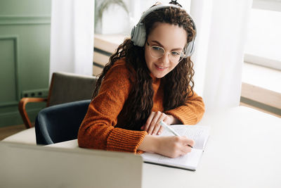 Happy young woman elearning on laptop from home attending webinar with headphones. smiling student