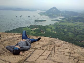 Man sitting on mountain by river