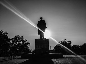 Rear view of silhouette man statue against sky in city