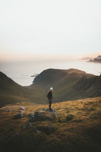 Rear view of man standing on shore against sky