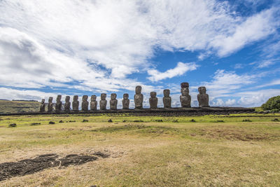 Statues on land against cloudy sky