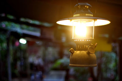 Close-up of illuminated lamp hanging on street at night