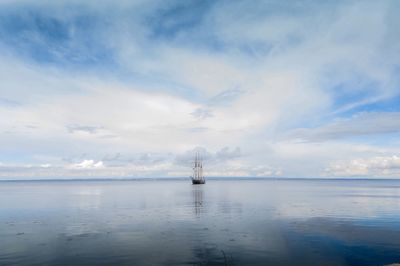 Boats in sea against cloudy sky