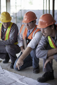 Male architect explaining plans to construction workers on site