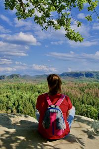 Rear view of woman sitting on land against sky