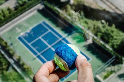 Cropped hand of man holding ball over playing field