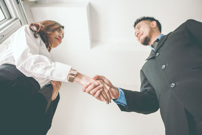 Low angle view of business colleagues shaking hands in office