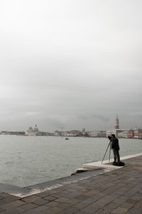 Man on pier over sea against sky