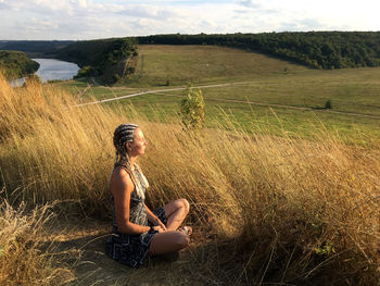 Side view of woman sitting on field