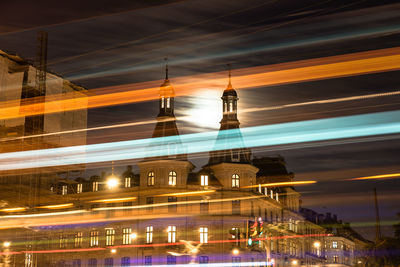 Low angle view of light trails in illuminated city at night