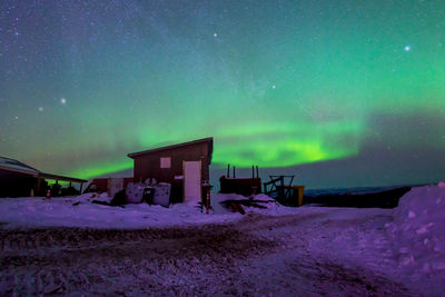 Built structure on snow covered land against sky at night