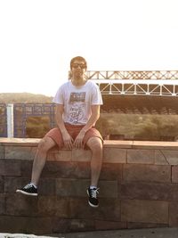 Portrait of young man sitting against clear sky