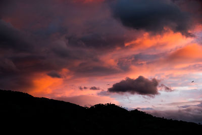 Low angle view of silhouette mountains against dramatic sky