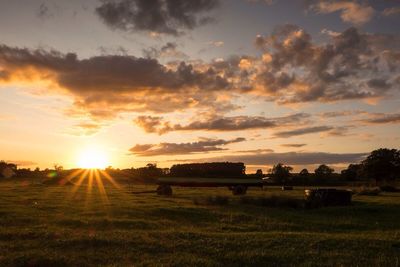 Scenic view of grassy field against sky at sunset