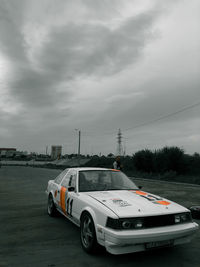 Car on street against cloudy sky