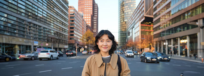 Portrait of young woman standing in city