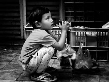 Side view of cute boy sitting on looking away