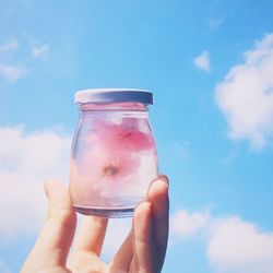 Close-up of hand holding glass jar filled with water and flowers