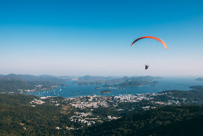 People paragliding over cityscape against sky