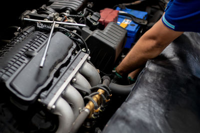 Cropped hand of mechanic repairing car engine at garage