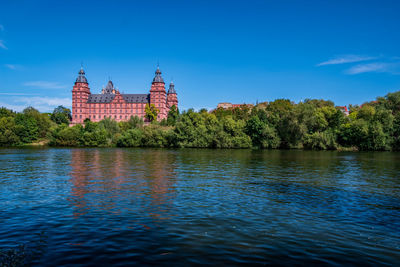 View of lake by building against blue sky