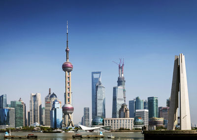 Communications tower in city against clear sky