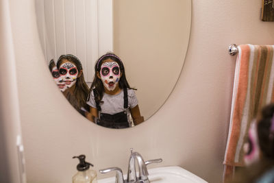 Sisters with face paint looking into mirror