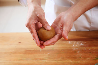 Midsection of woman preparing sweet baking food with dough at kitchen counter