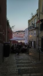 People on street amidst buildings in city at dusk