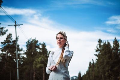 Portrait of young woman standing against sky