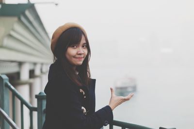 Portrait of smiling young woman against sky