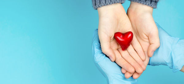 Midsection of woman holding heart shape against blue background