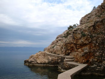 Cliff by sea against sky