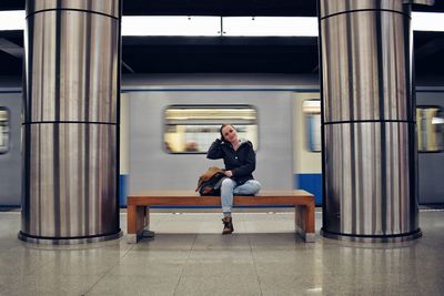 Full length of woman sitting on subway platform