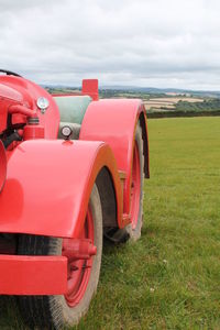 Red tractor on land against sky