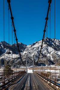 Railroad tracks by snowcapped mountains against clear sky