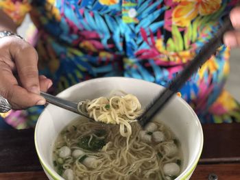 Midsection of person having food noodle on table 
