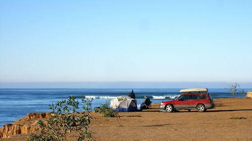 Car parked by sea against clear sky