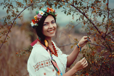 Portrait of smiling young woman standing by tree