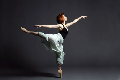 Ballerina dancing against gray backdrop