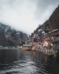 Houses by lake and buildings against sky