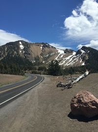 Road by mountains against sky