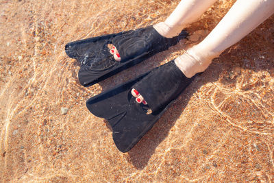 Low section of woman standing on sand at beach