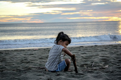 Full length of boy on beach against sky during sunset